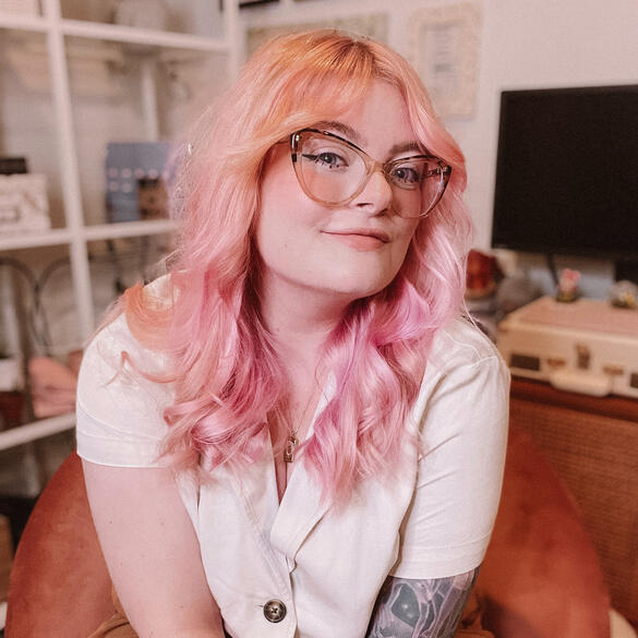 OliviaMariePortrait A portrait of Olivia, a white woman with pink hair and glasses.